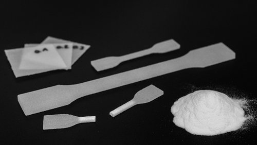 Im PBF-Prozess hergestellte Monolayer (Plättchen) und Zugstäbe sowie eine Probe des verwendeten PP-Pulvers Rolaserit PP01 von AM Polymers. (Foto: Luca Hoffmannbeck/SKZ)