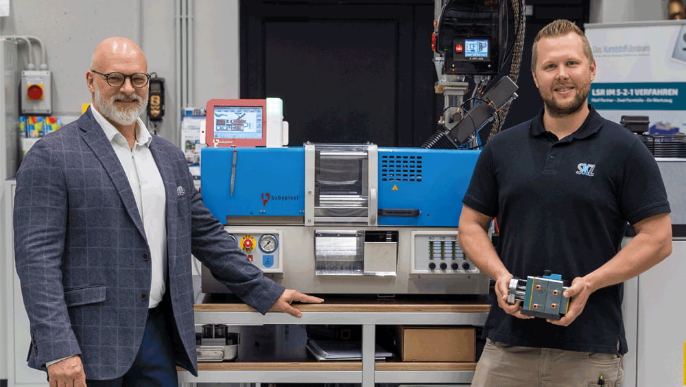 Marc Tesche (links), Geschäftsführer CHRISTMANN Kunststofftechnik GmbH, und Christoph Mussauer (rechts), Leitung Spritzgießtechnikum, vor der neuen SKZ-Maschine mit einem ersten Werkzeug