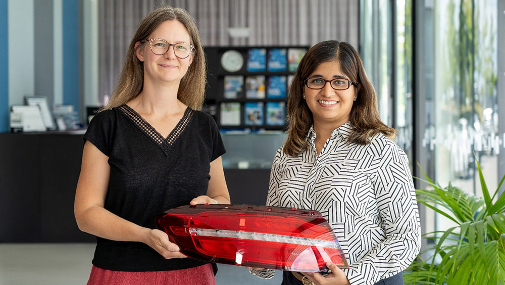 Zwei Frauen stehen im Foyer der Modellfabrik des SKZ mit einem Rücklicht eines Automobils
